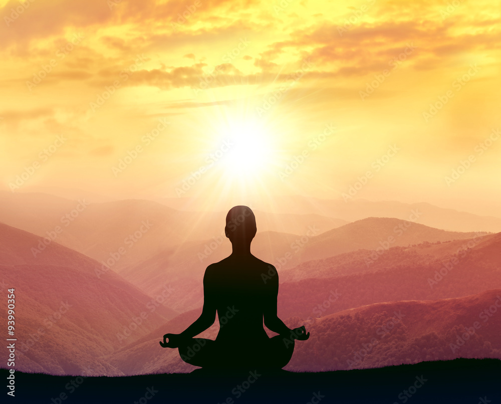  Man meditating in the mountains. Silhouette of man.