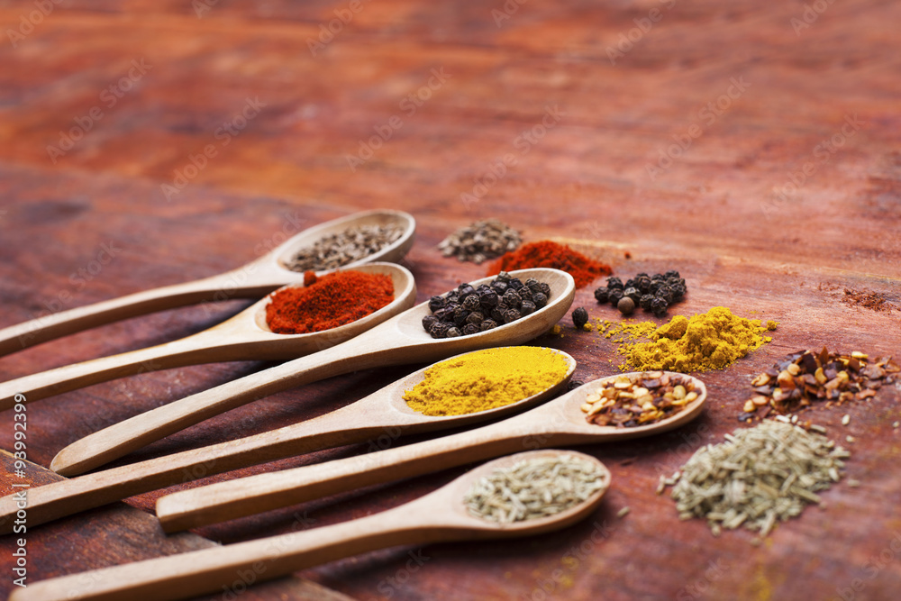Wooden spoons full of aromatic herbs and spices on a wood cuttin Wooden spoons full of aromatic herbs and spices on a wood cuttin