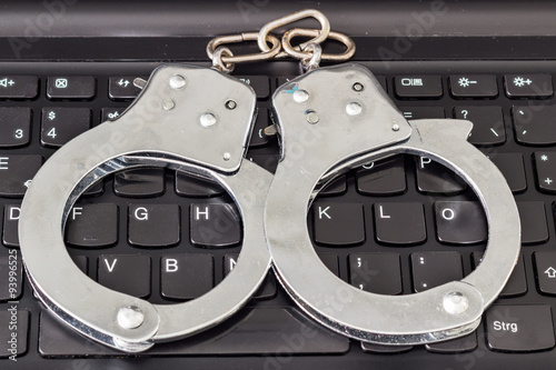 Handcuffs on keyboard, symbolizing computer security and police investigation