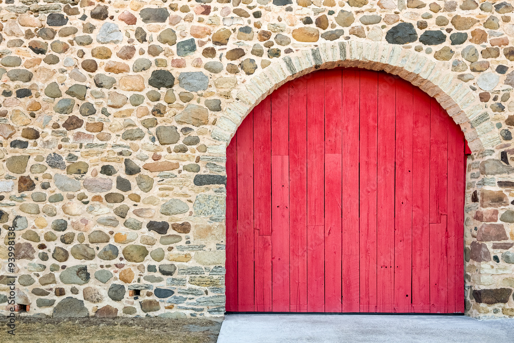 Fototapeta premium Bright Red Arched Door in a Stone Wall