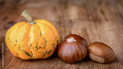 small decorative pumpkin and chestnut on wood