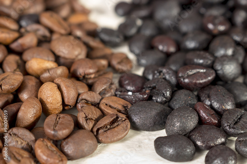 Natural roasted coffee beans and torrefacto coffee beans on a white table