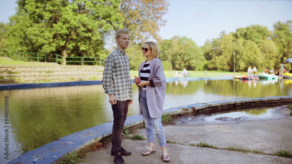Couple standing in the park next to the river and chatting
Couple standing in the park next to the river and chatting