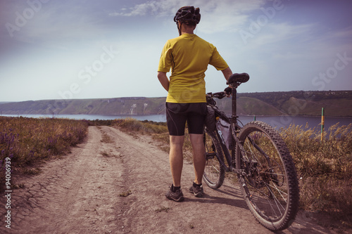 Young bicyclist relax in beautiful nature near river