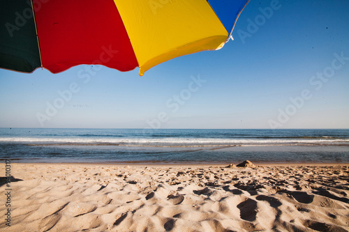 Colorful beach umbrella on the golden sand. Summer vacation concept