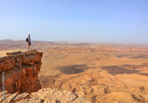 Magic desert landscape / View of Negev stone desert.Traveler on a cliff in the  National geological park HaMakhtesh HaGadol,Large Crater - geological erosion land form, Israel 