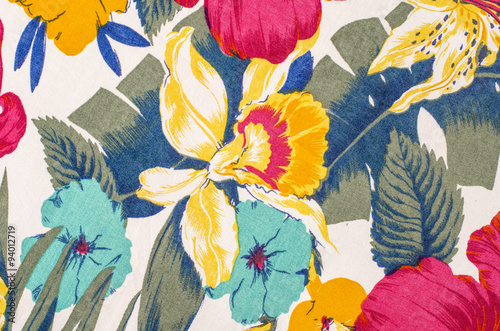 Floral pattern on white fabric. Colorful exotic flowers with green and blue leaves print as background.