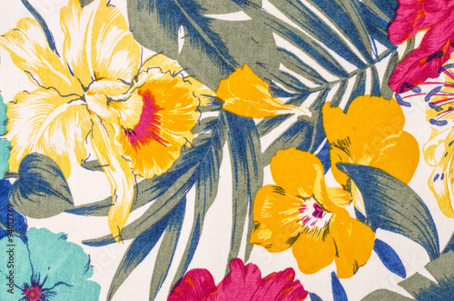 Floral pattern on white fabric. Colorful exotic flowers with green and blue leaves print as background.