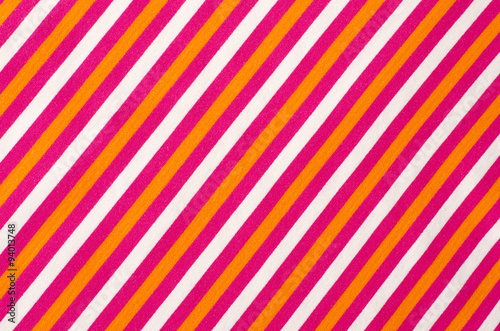 Striped pink and orange with white textile pattern as a background. Close up on diagonal stripes material texture fabric.