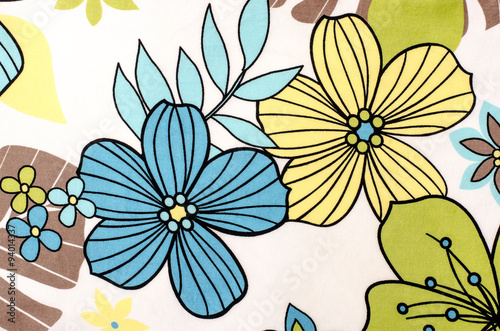 Floral pattern on white fabric. Colorful exotic blue and yellow flowers print as background.