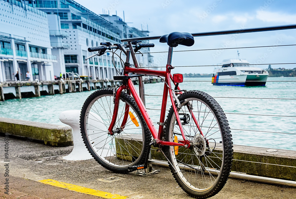 Red parked bicycle on the pier at harbor