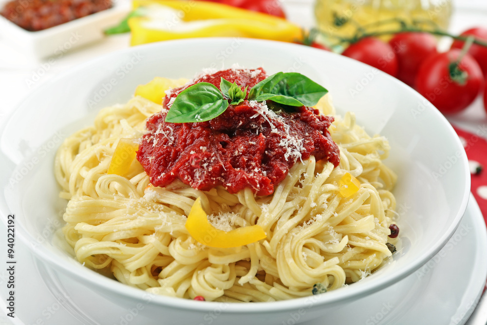 Spaghetti with tomato sauce and cheese on white plate, on color wooden background