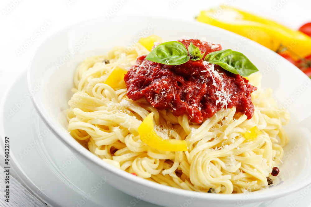 Spaghetti with tomato sauce and cheese on white plate, on color wooden background