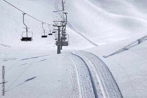 Wyciąg krzesełkowy i ślady ratraka (snowgroomer) w śniegu na przełęczy Presena, Passo Tonale