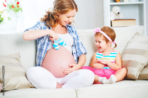 happy family pregnant mother and child daughter preparing clothi photo