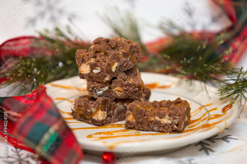 Homemade turtle brownies on serving plate with Christmas background
