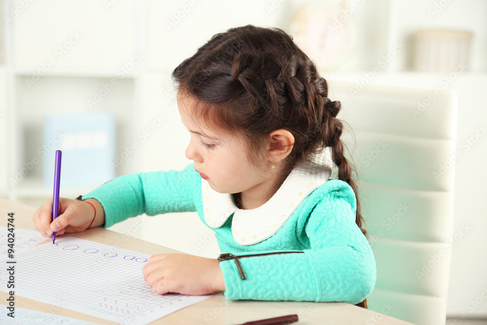 Cute little girl doing her homework, close-up, on home interior background Cute little girl doing her homework, close-up, on home interior background