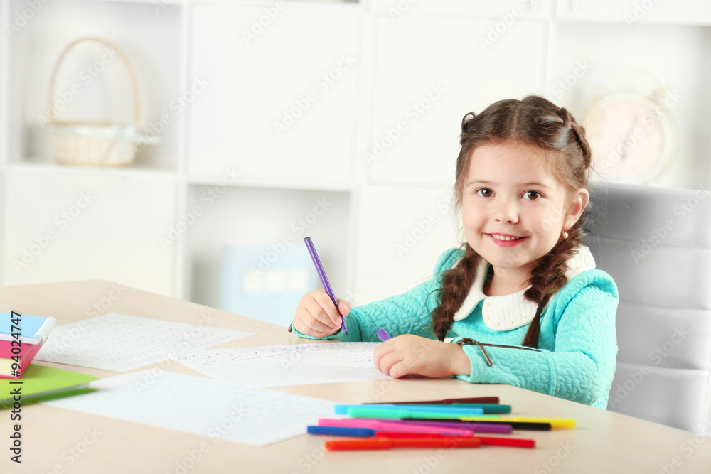 Cute little girl doing her homework, close-up, on home interior background Cute little girl doing her homework, close-up, on home interior background