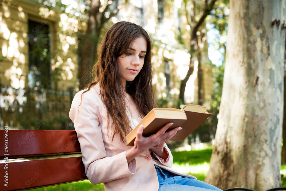 Obraz premium young caucasian female student reading a book on campus, student study in campus area