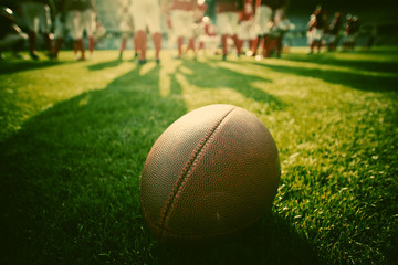 Close up of an american football on the field, players in the ba