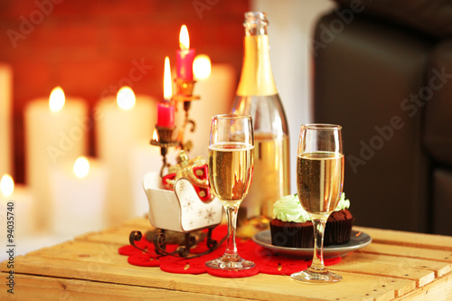 Delicious cupcakes and champagne on home interior background