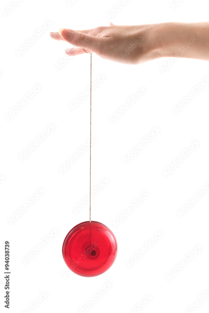 Fototapeta premium A hand holding a red yoyo as it goes up and down, isolated on white.