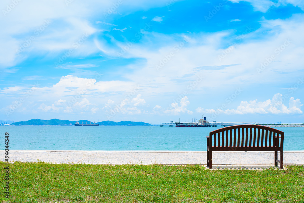 An empty wooden bench with a viewpoint looking out to sea. An empty wooden bench with a viewpoint looking out to sea.