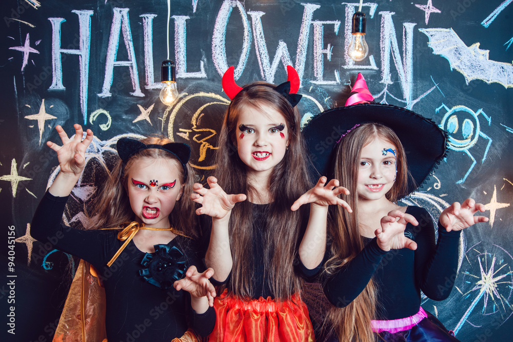 Girls, dressed up in Halloween costumes, show emotions of witches . Halloween party with group children.