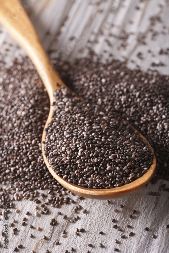 Chia seeds in a wooden spoon on the table close-up. vertical