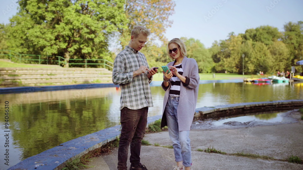 Couple standing next to the river and using smartphones
Couple standing next to the river and using smartphones