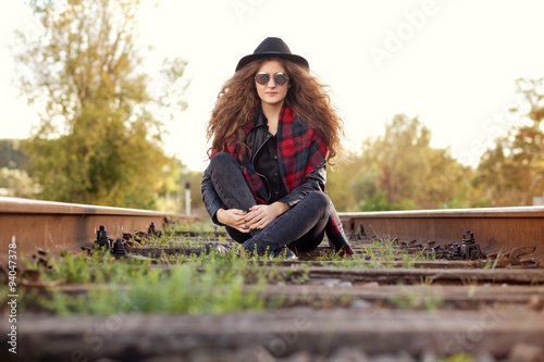 девушка сидит на рельсах в солнечную осеннюю погоду