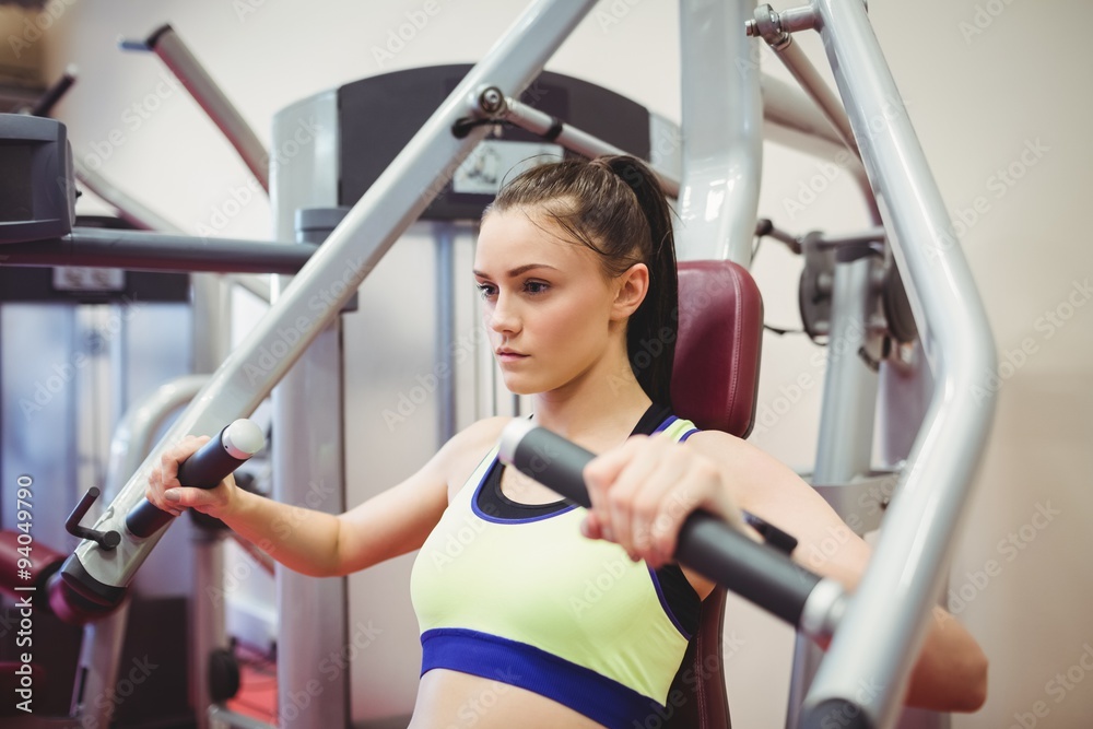 Fit woman using weights machine for arms Fit woman using weights machine for arms