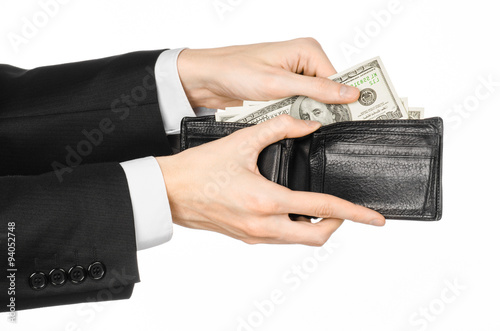 Money and business topic: hand in a black suit holding a wallet with dollar banknotes isolated 