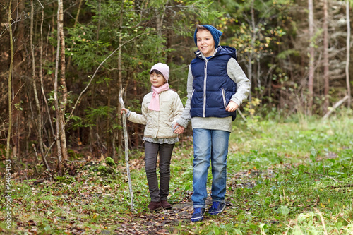 two happy kids walking along forest path