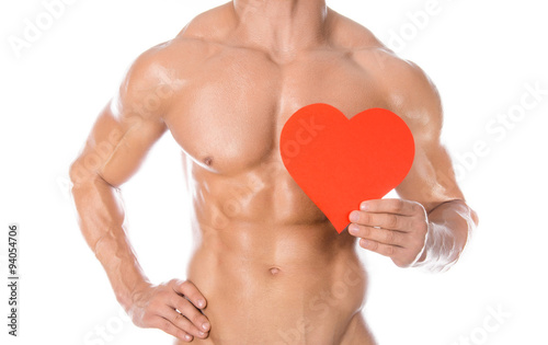 Bodybuilding and Health: handsome strong bodybuilder holding a paper card red heart isolated on a white background in studio