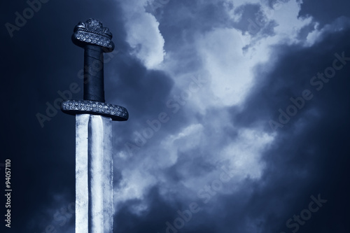 Medieval viking sword against a dramatic sky