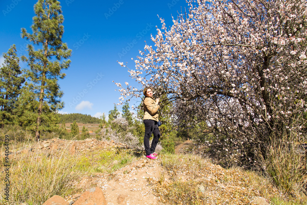 Naklejka premium Young woman standing under blooming tree