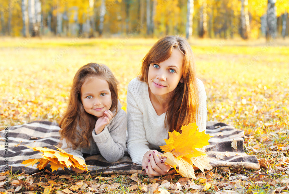 Mother and child together with yellow maple leafs in autumn day