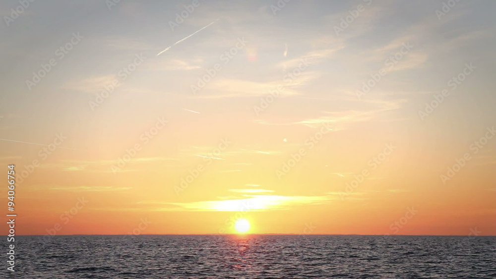 The bright sun is setting over water with gentle waves The bright sun is setting over water with gentle waves