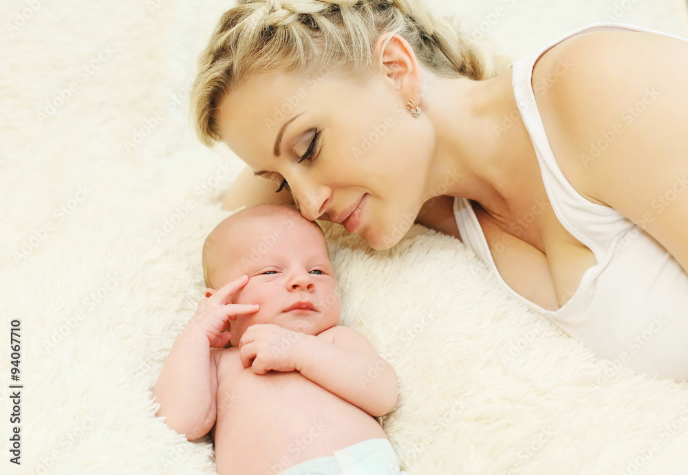 Happy smiling mother with baby lying on bed together at home Happy smiling mother with baby lying on bed together at home