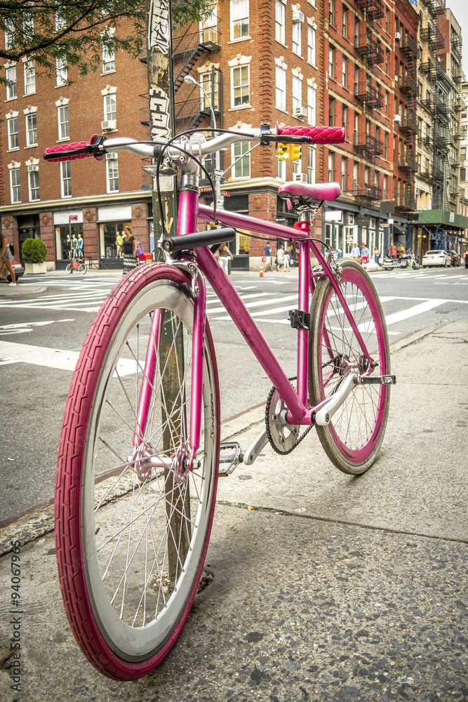 Pink bicycle on a quiet street in SOHO, New York with a brick building in the background