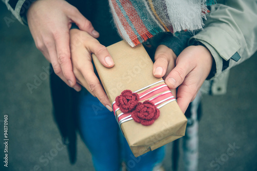 Woman and man hands showing gift box otdoors photo