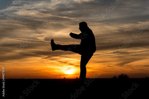 People Silhouette   Man makes kickboxing in the sunset
