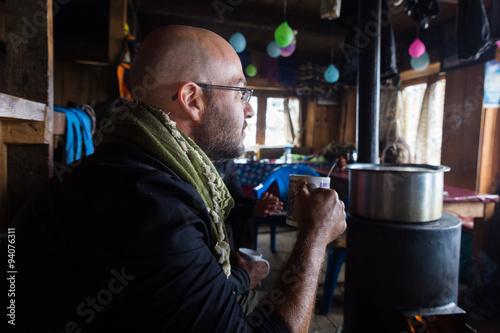 Фотография Man tourist guy sitting lodge guest house fireplace holding cup, resting