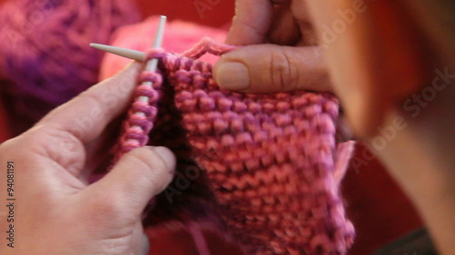 Winter time. Woman hands knitting wool close up. High angle camera view from the shoulders.