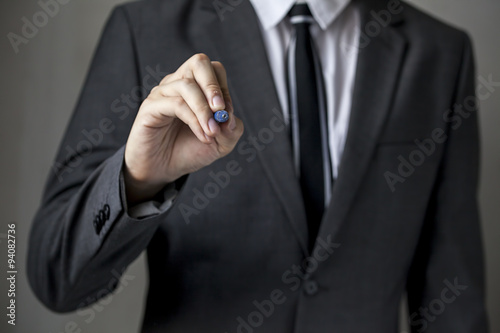 Close-up of front faced businessman is writing on the board (focus on hand, blur out the suit). It can be used for layout in business-related words and objects. 