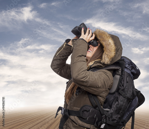 beautiful young woman hiker looking through binoculars