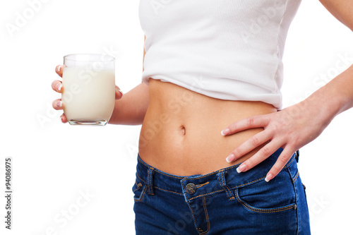 belly of a young woman with a glass of milk in a white background