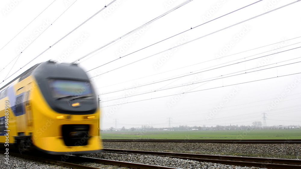 Yellow and blue passenger train passing by at high speed.