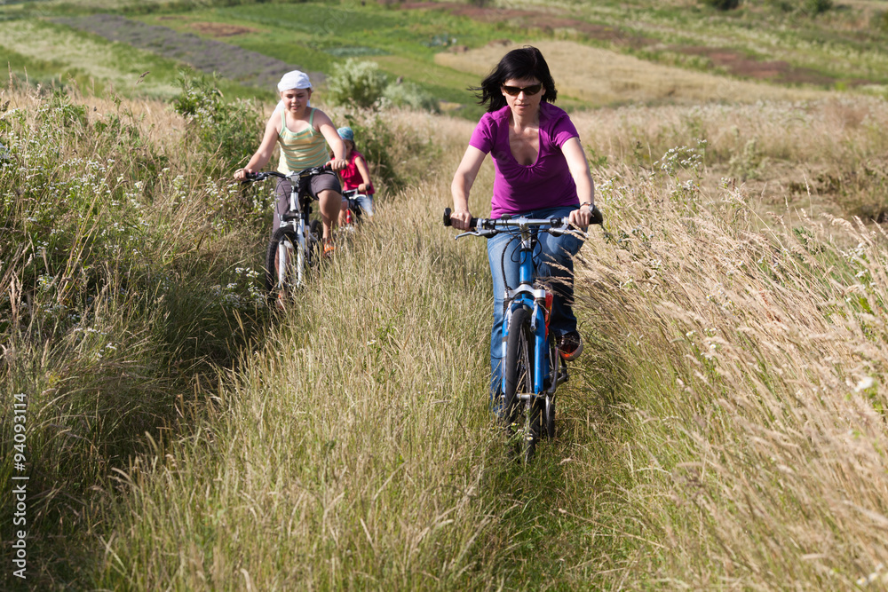 Fototapeta premium Family riding a bicycles in the meadow
